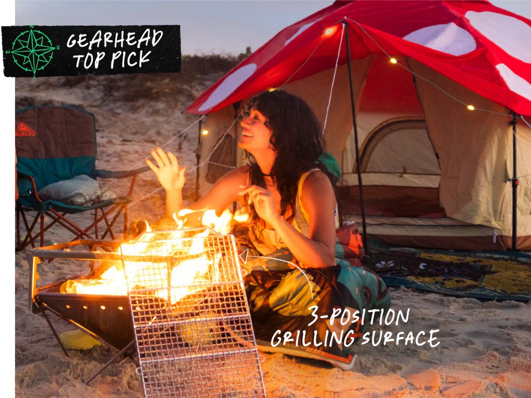 A smiling person sits at a fire pit in front of a tent that looks like a mushroom. Text overlay reads: Gearhead top pick, 3-position grilling surface.